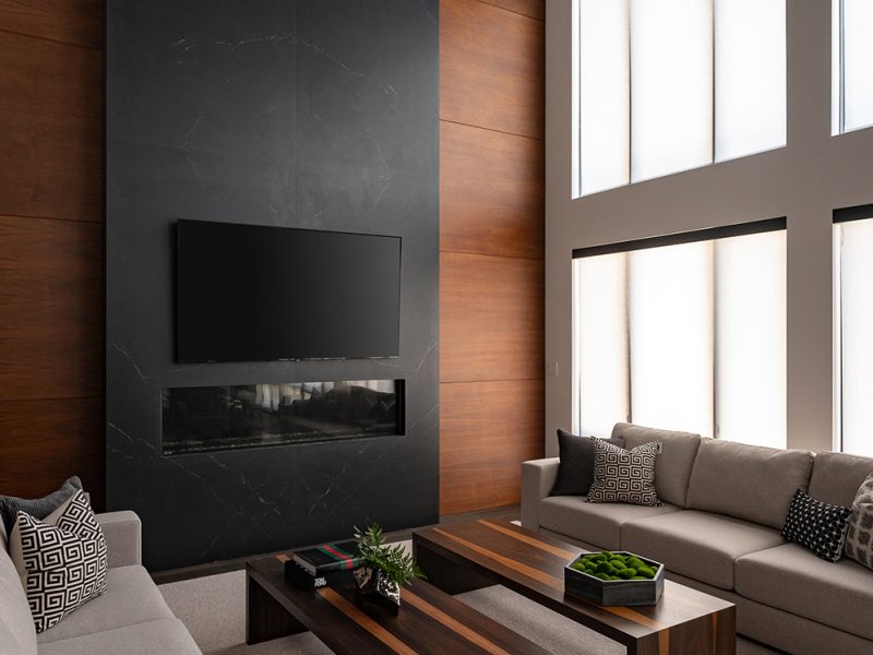 Large fireplace wall with black stone and walnut panel