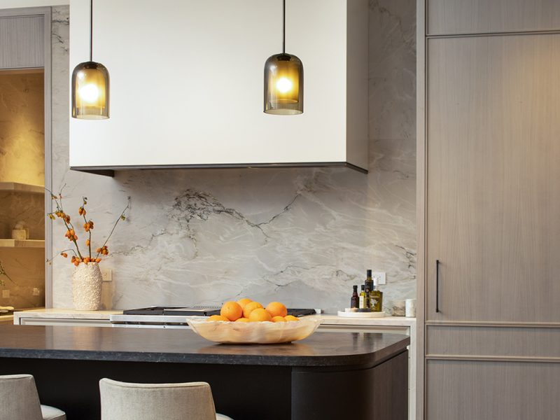 Dark curved kitchen island with light cabinets