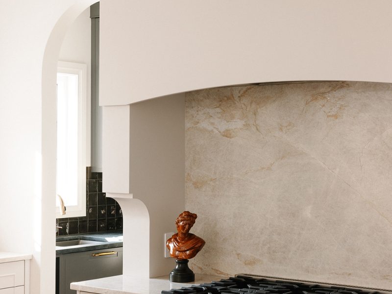 Curved range hood with corbel details and Taj Mahal backsplash
