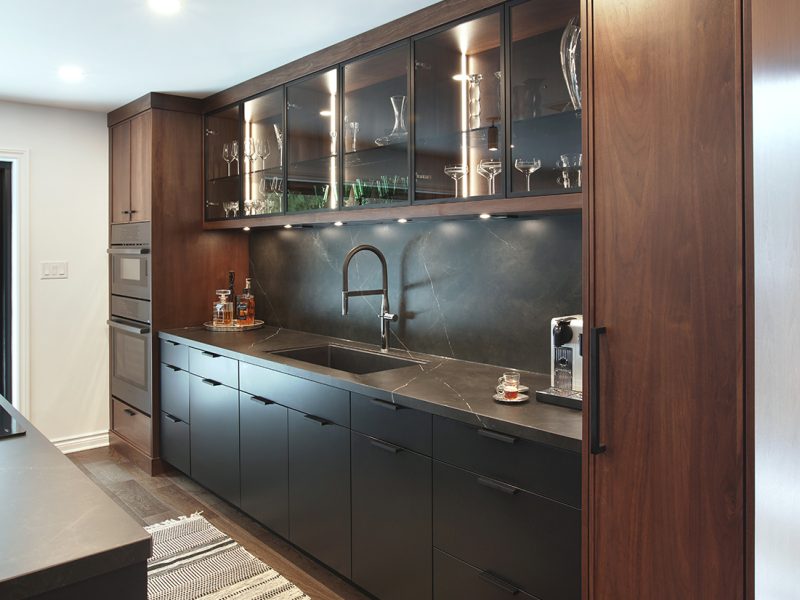 Sink wall with two tall walnut towers and glass cabinets
